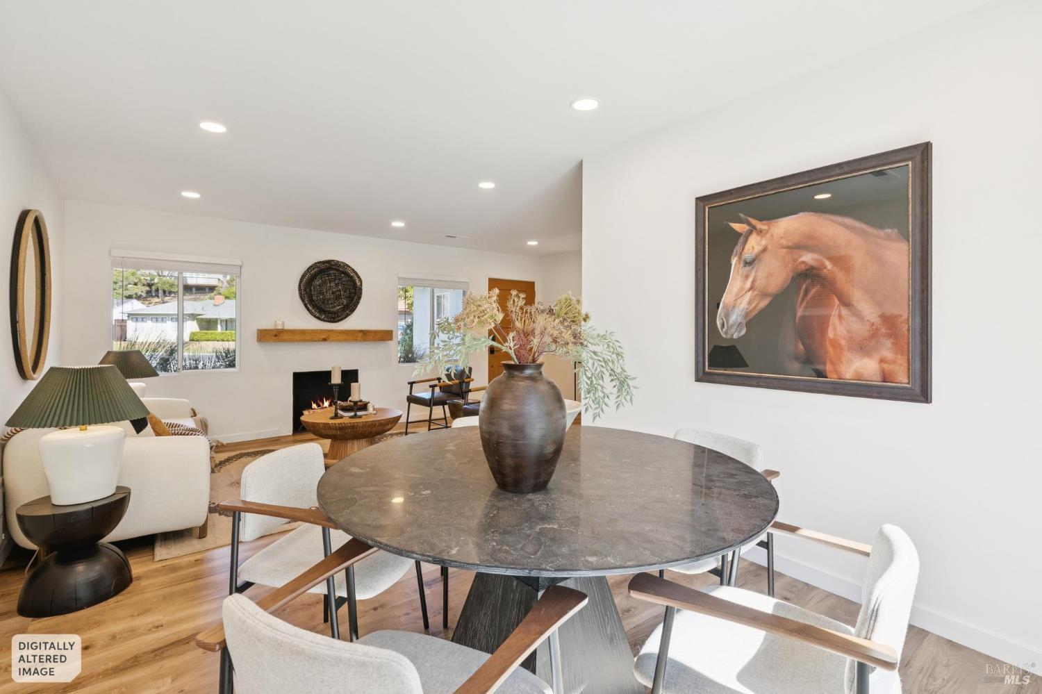 Dining area with a round stone table, upholstered chairs, and an adjoining living room with a fireplace.