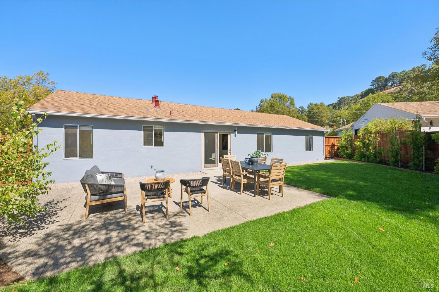 Rear of a single-story home with a furnished patio and green lawn.