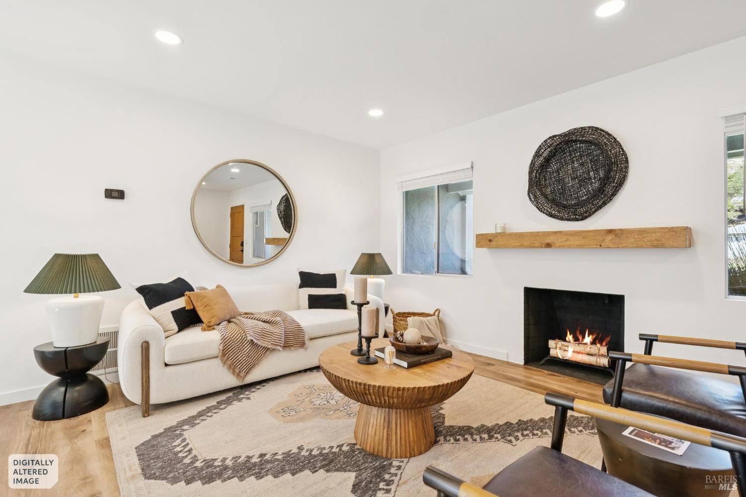 Staged living room with a white sofa, round wood coffee table, and lit fireplace.