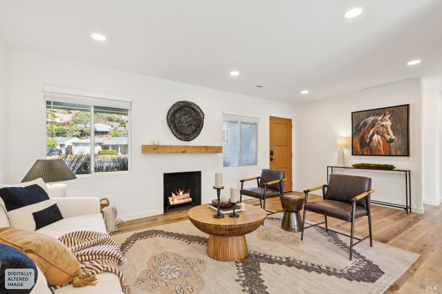 Staged living room with a fireplace, leather armchairs, and large windows.