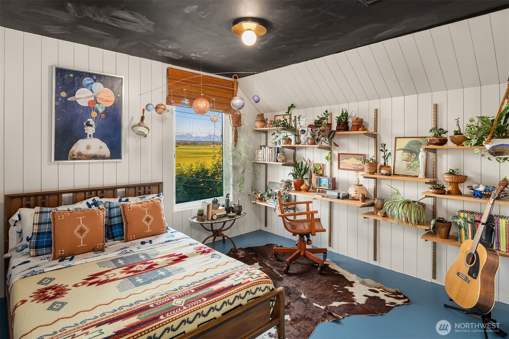 Bedroom with patterned bedding, plant-filled shelves, and a hanging solar system model.