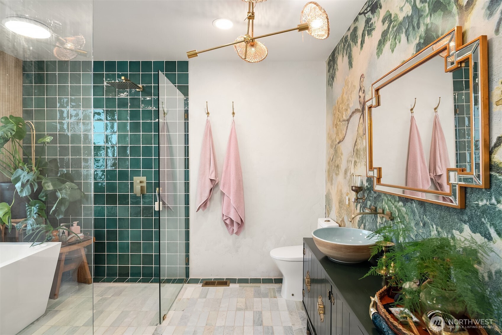 Bathroom with a green-tiled glass shower, freestanding tub, botanical mural, and vessel sink.