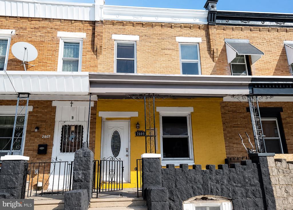 Attached rowhouses with brick upper stories, a yellow facade, and a dark stone front wall.