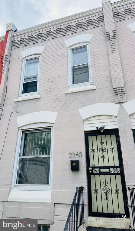 Pale brick rowhouse at 2260 with white-trimmed windows and a black decorative metal entry door.