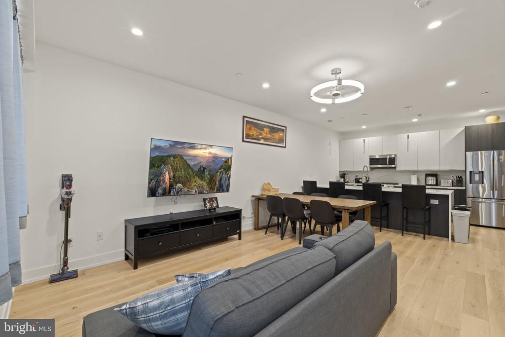 Open-plan living room with gray sofa, dining table, and modern white kitchen.