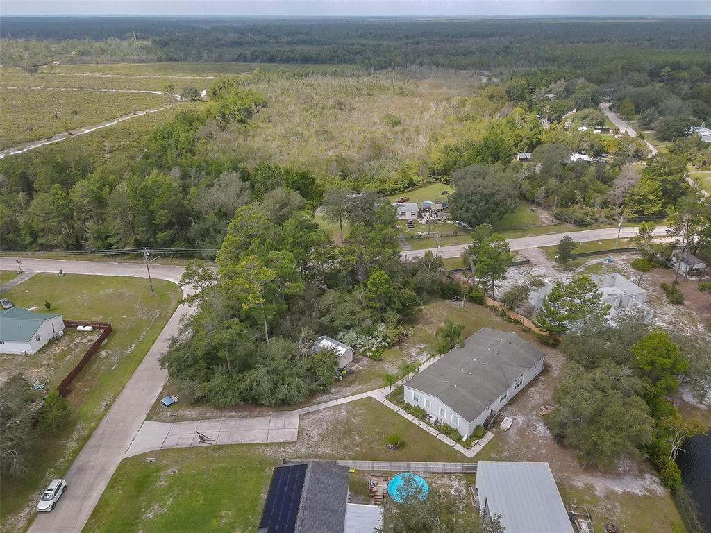 Aerial view of manufactured homes and wooded lots amid rural roads and wetlands.
