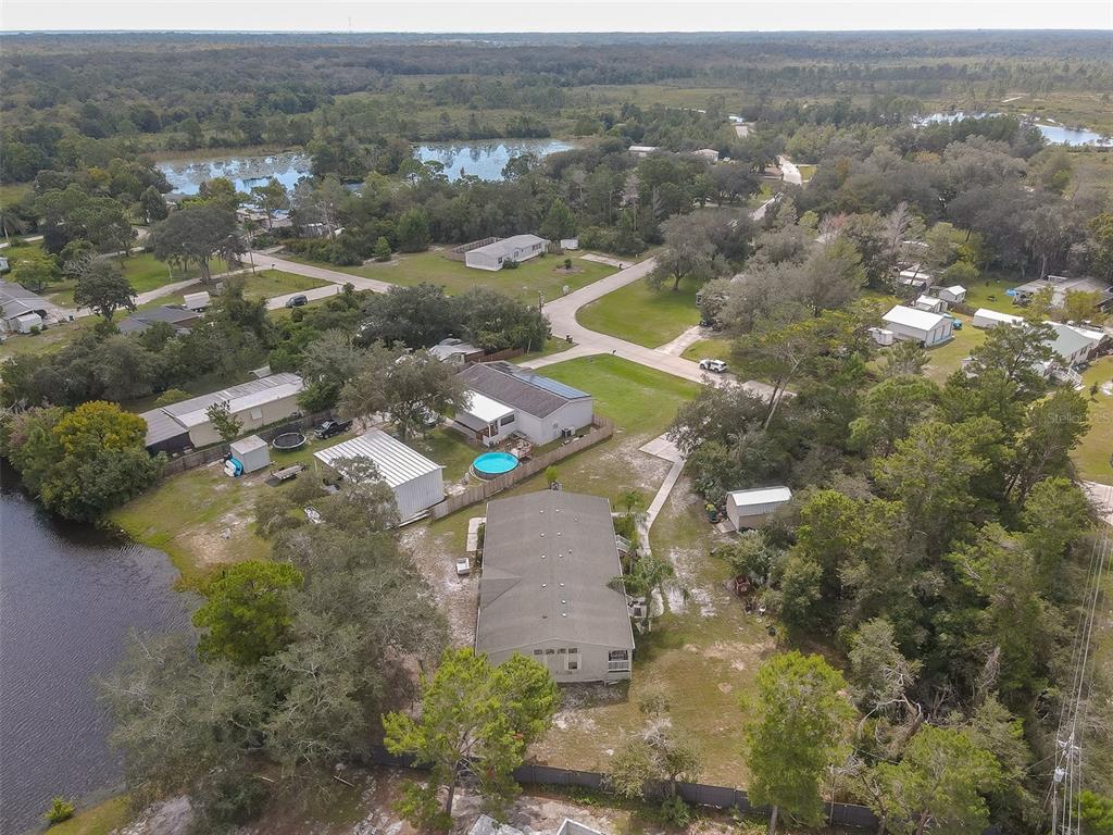 Aerial view of a home with a fenced yard and pool near a lake.