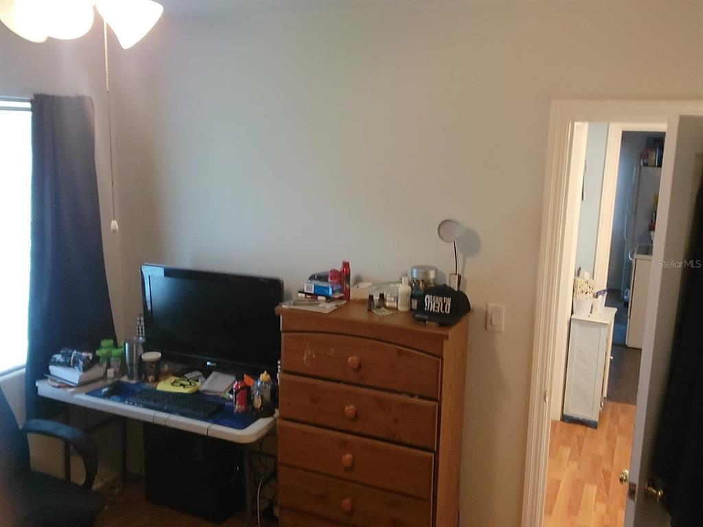 Bedroom with a computer desk, wooden dresser, and open doorway to a bathroom.