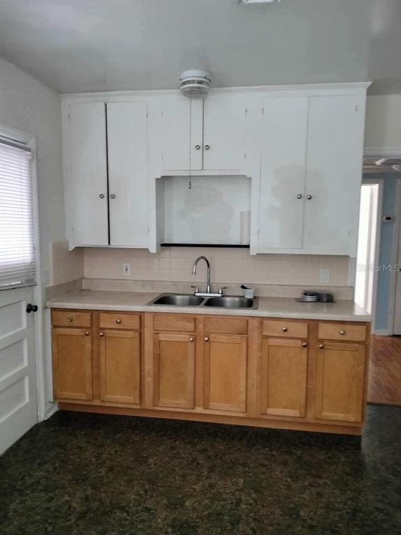Kitchen with white upper cabinets, wood lower cabinets, and a stainless double-basin sink.