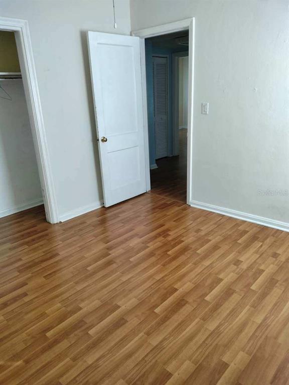 Empty room with wood-look flooring, a closet opening, and an open door to the hallway.