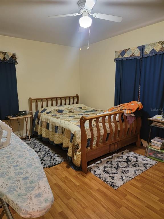 Furnished bedroom with two beds, a wooden bed with a patchwork quilt, and blue curtains.