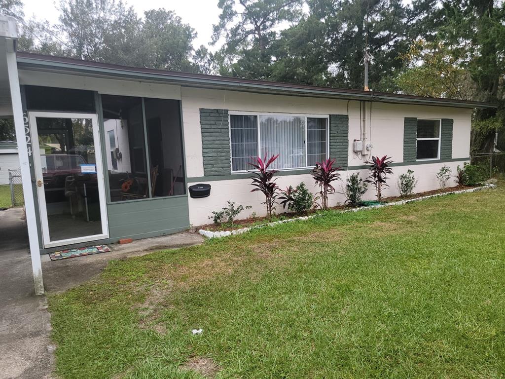 Single-story home with dark green trim, a covered entry, and landscaped front lawn.