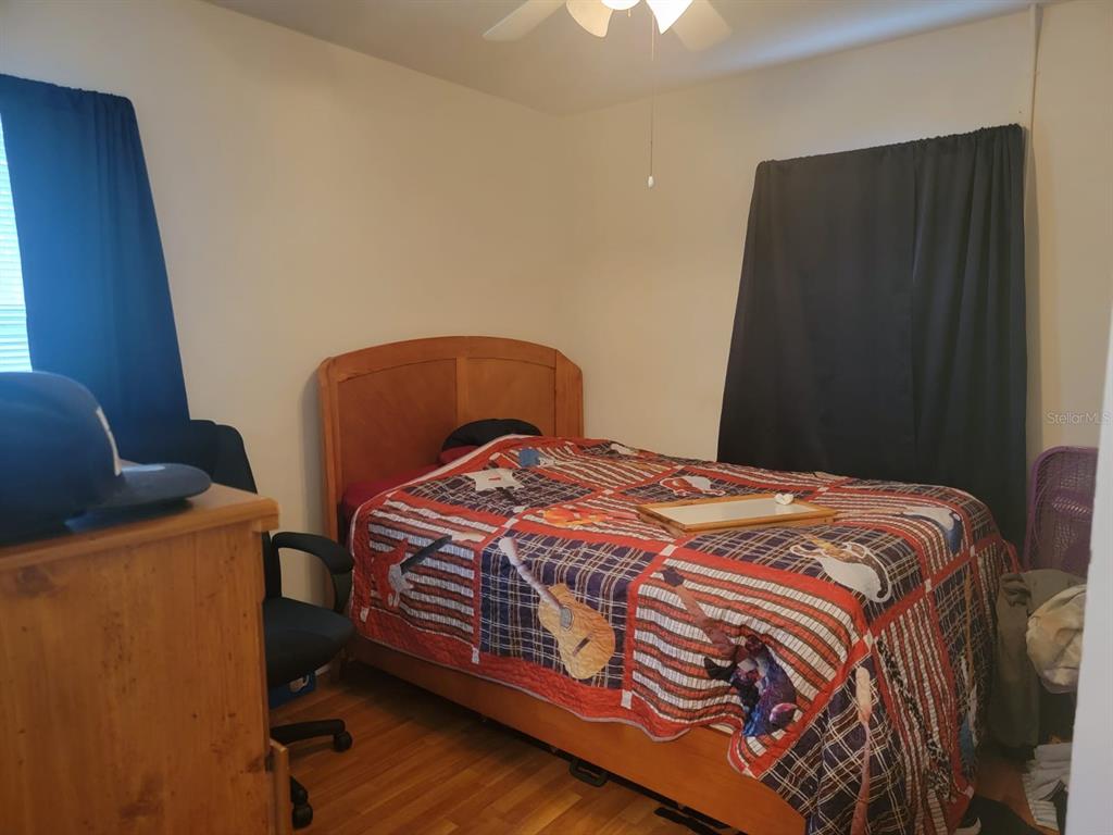 Bedroom with a wooden bed covered in a colorful patchwork quilt and a wooden dresser.