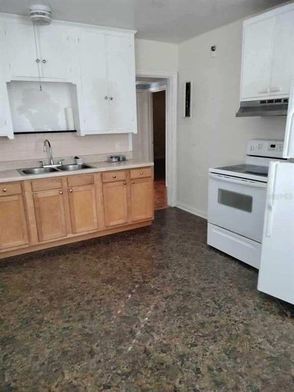 Kitchen with white upper cabinets, light wood lower cabinets, and dark patterned flooring.