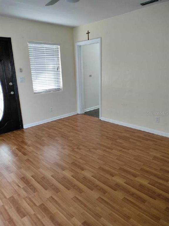Vacant room with wood-look flooring, a window with white blinds, and an open doorway.