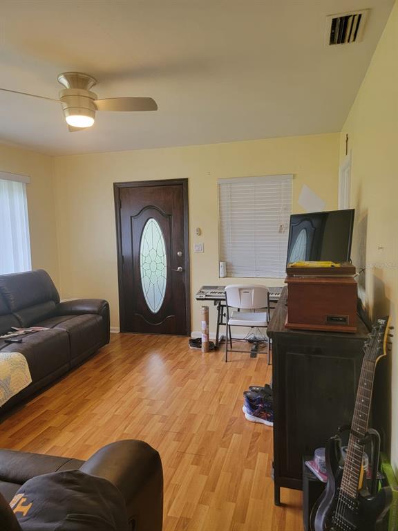 Living room with leather sofas, wood-look flooring, and a decorative glass-paneled front door.