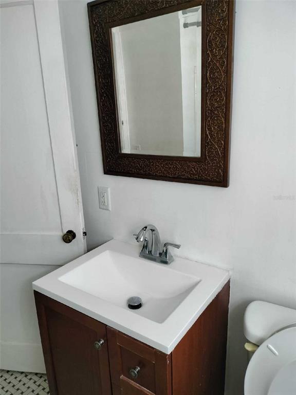 Bathroom with a dark wood vanity, white sink, and ornate framed mirror.