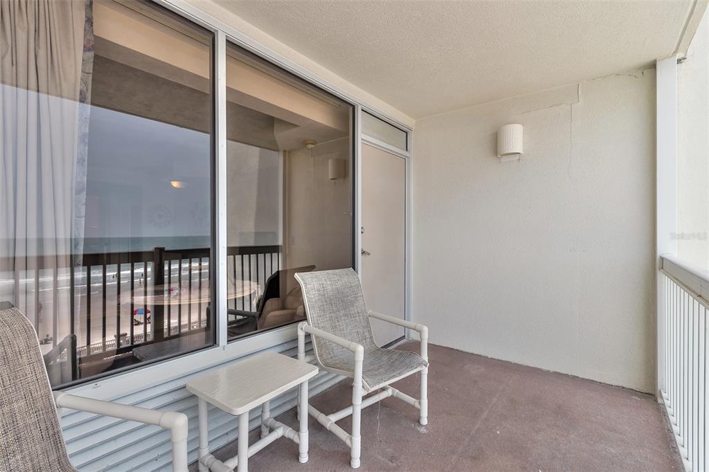 Furnished condo balcony with two chairs and an ocean view.