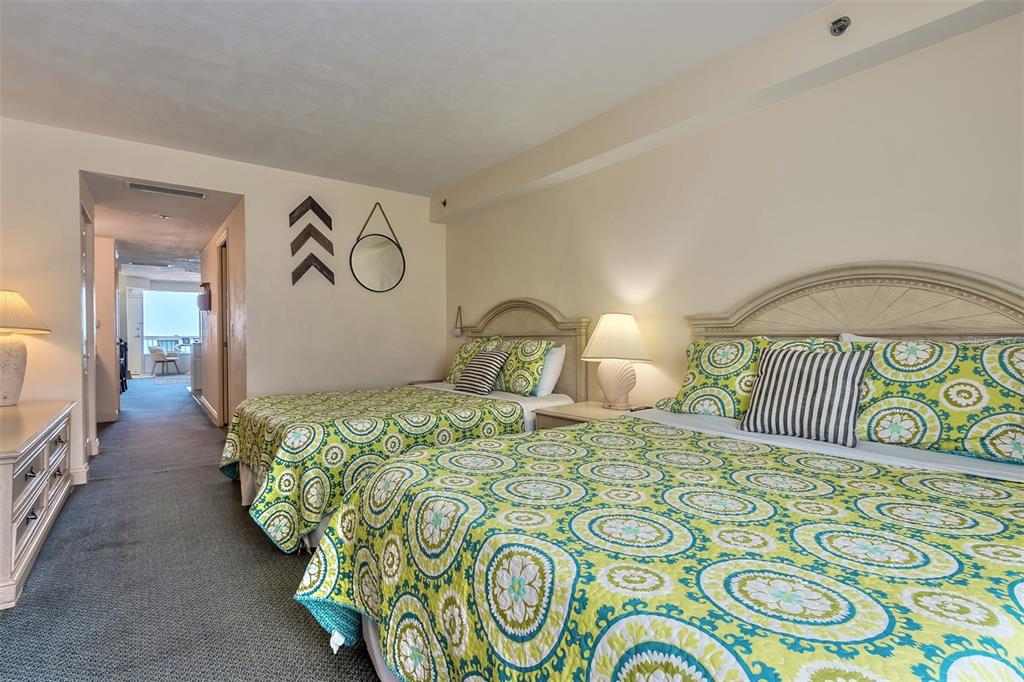 Bedroom with two beds, patterned green bedding, and arched headboards.