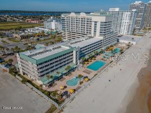 Aerial view of beachfront condominium buildings with pools and the Atlantic shoreline.