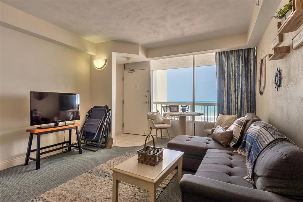 Furnished living room with a gray sectional and balcony overlooking the ocean.