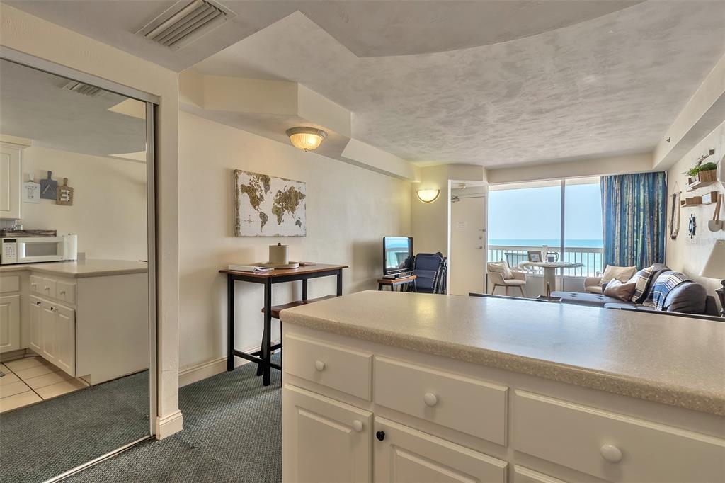 Condo kitchen and living area with a large island and ocean views through the balcony doors.