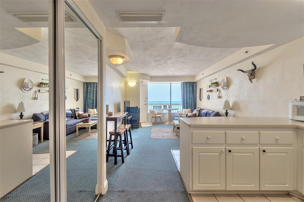 Furnished condo living area with blue seating and ocean views through sliding glass doors.