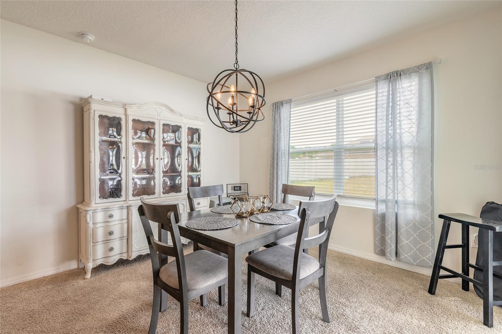 Dining room with a dark wood table, ornate white china cabinet, and spherical chandelier.