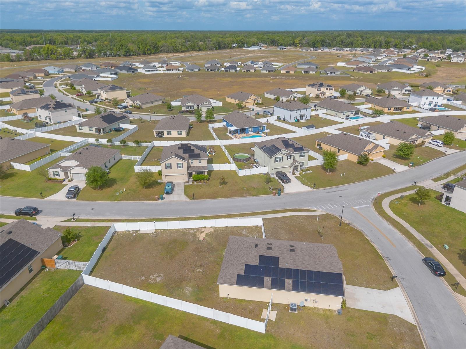 Aerial view of a residential subdivision with an open fenced lot in the foreground.