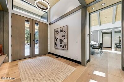 Modern home entry foyer with tall double doors, a patterned rug, and an open view into the dining area.