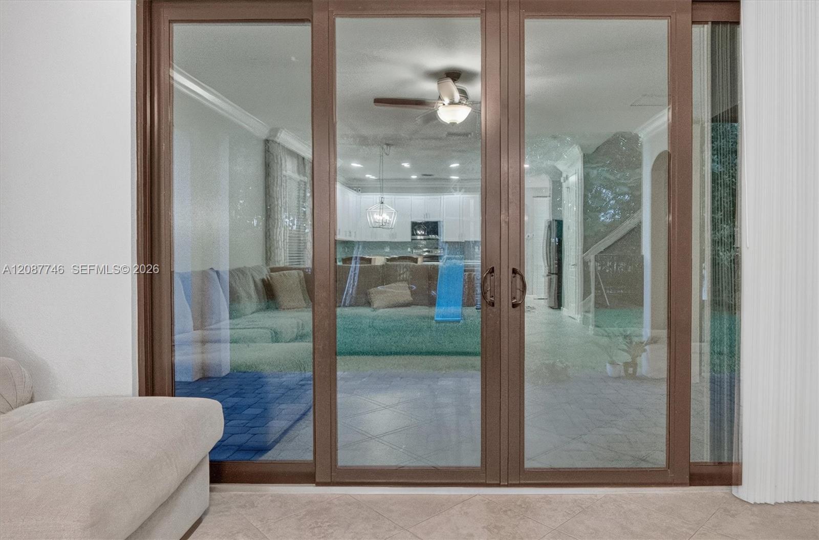 Living area with a light sectional sofa beside brown-framed sliding glass doors.