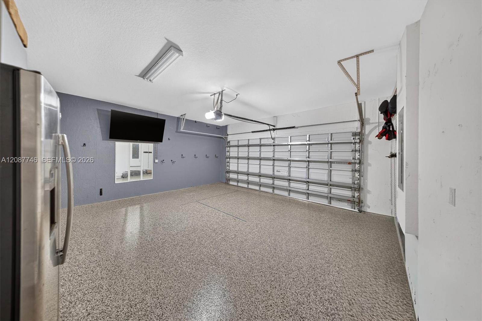 Empty garage with a speckled epoxy floor, gray walls, and a sectional garage door.