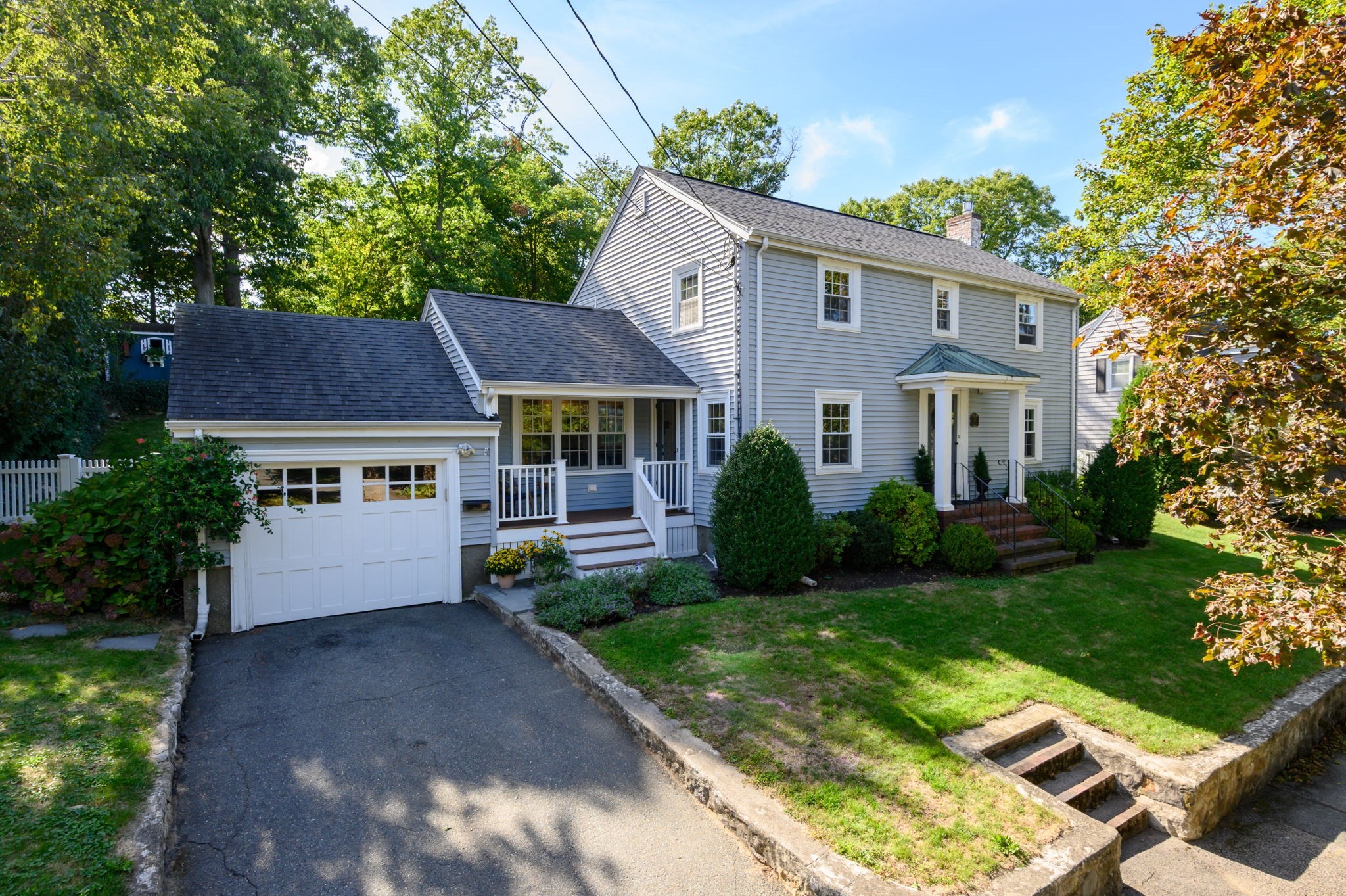 Two-story gray-sided house with an attached garage, covered entry, and landscaped front lawn.