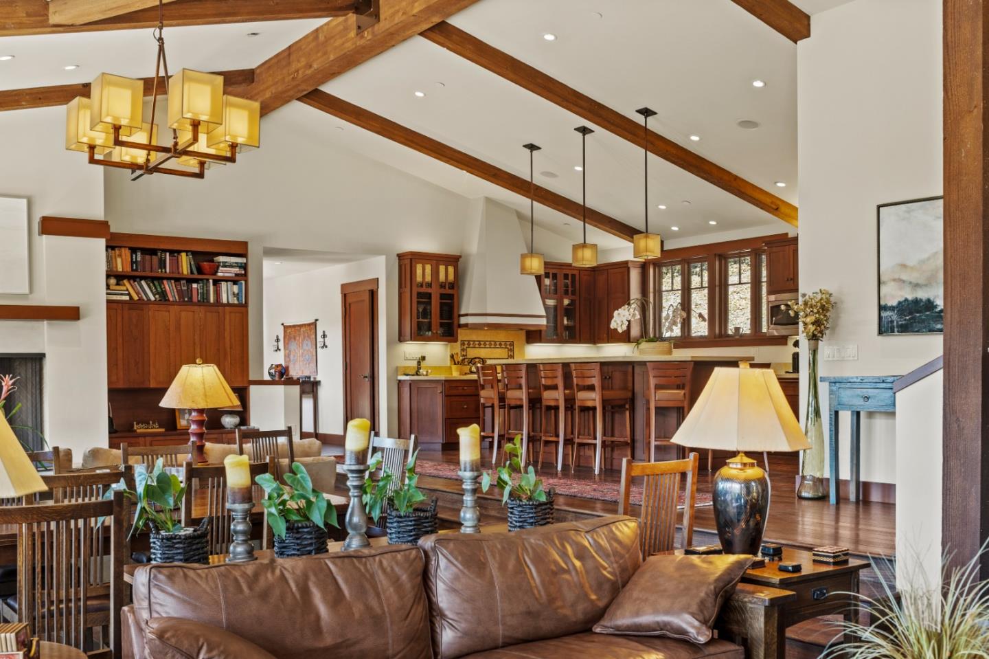 Open-plan living room and kitchen with vaulted wood-beam ceilings and dark wood cabinetry.