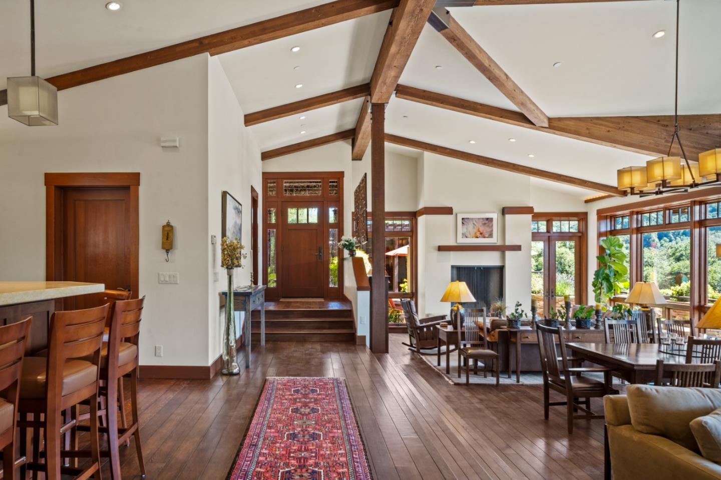 Open-plan living and dining room with vaulted wood-beam ceiling and fireplace.