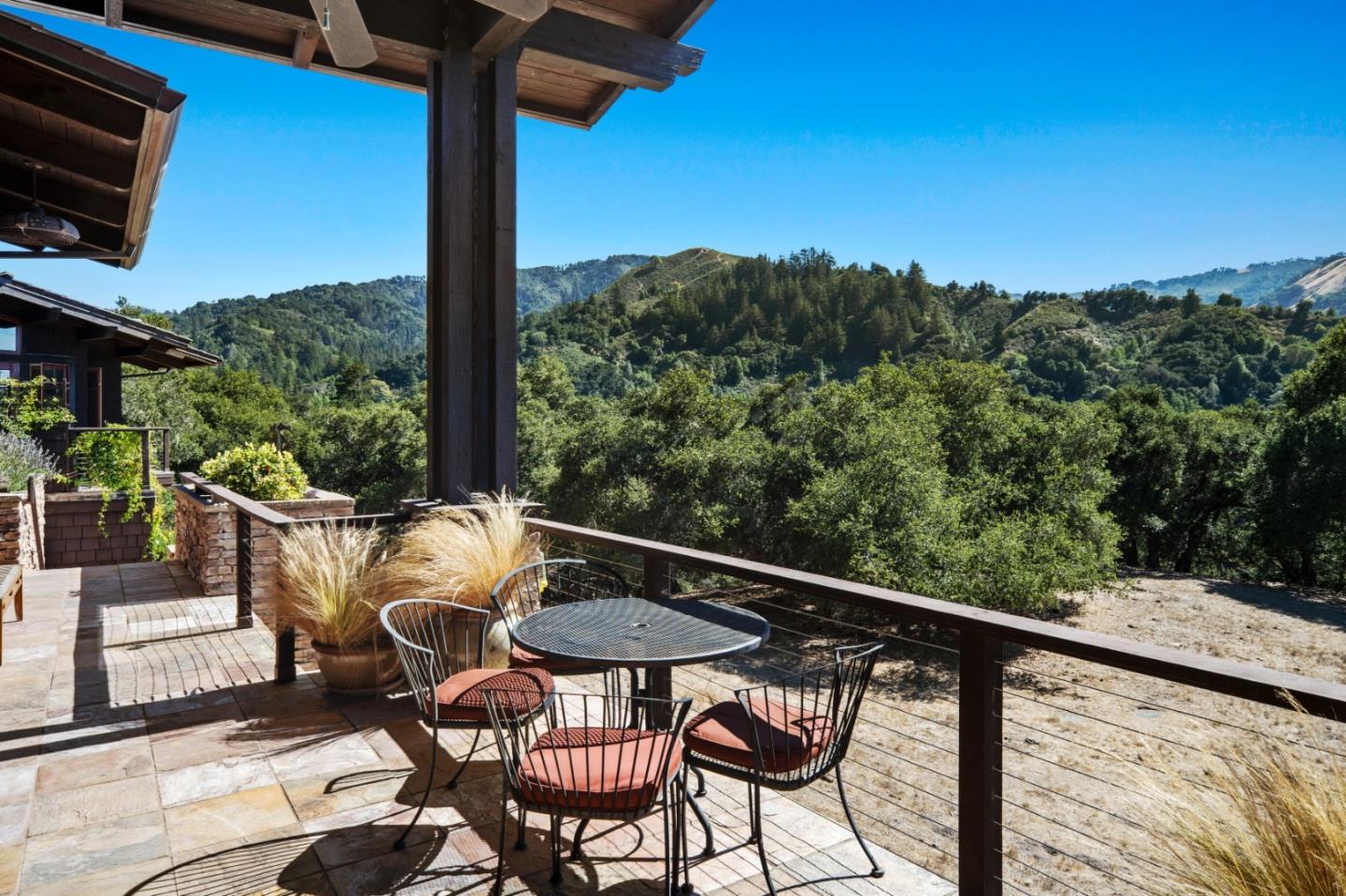 Stone terrace with outdoor dining set overlooking wooded hills and mountain ridges.