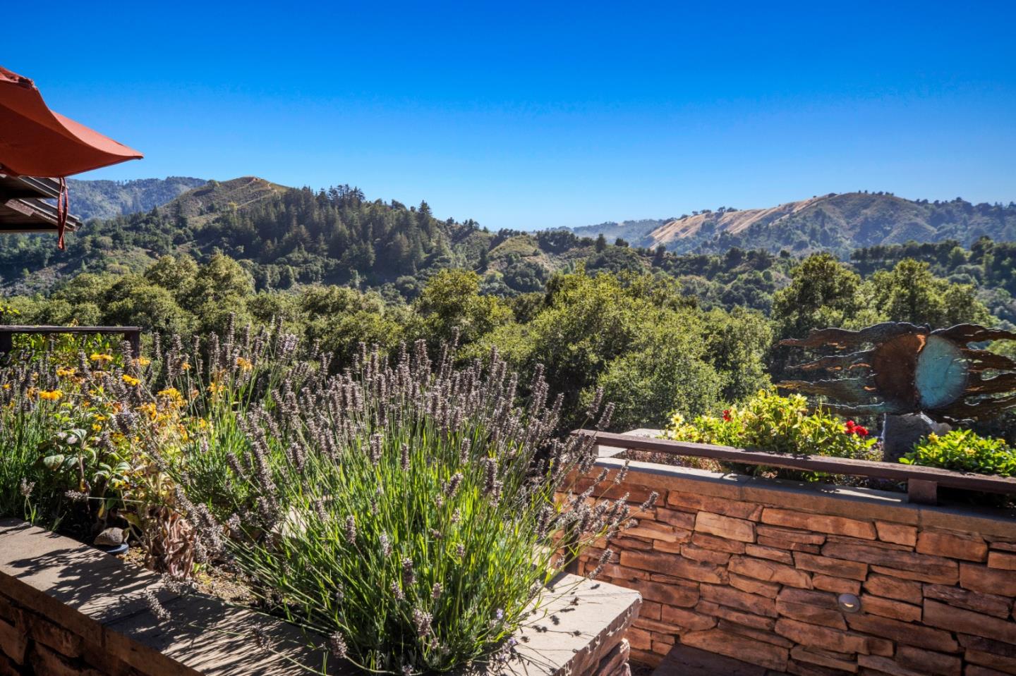 Stone terrace garden with flowering plants and broad views of wooded hills and mountains.