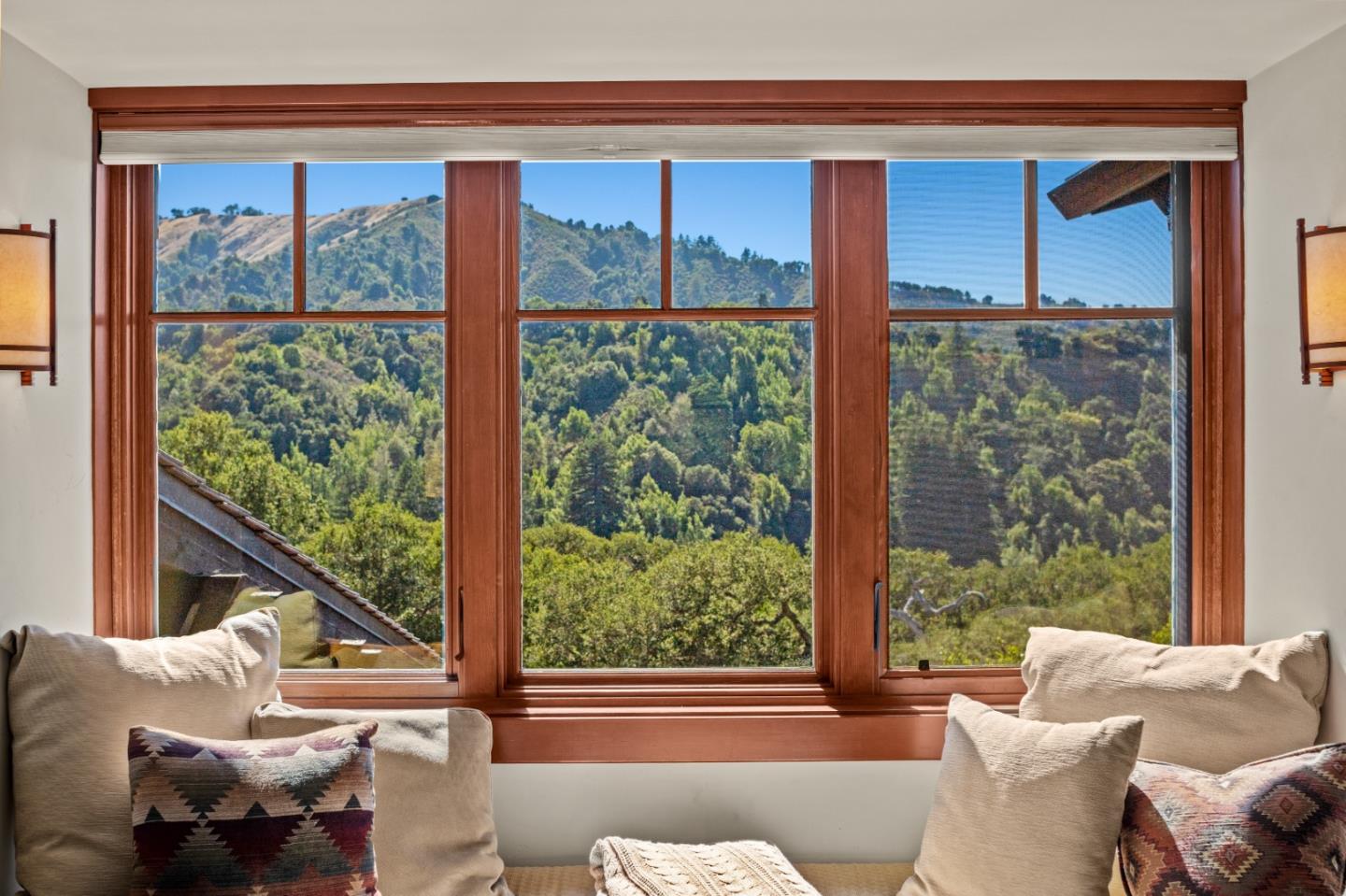 Living room with a large picture window overlooking wooded hills and mountains.