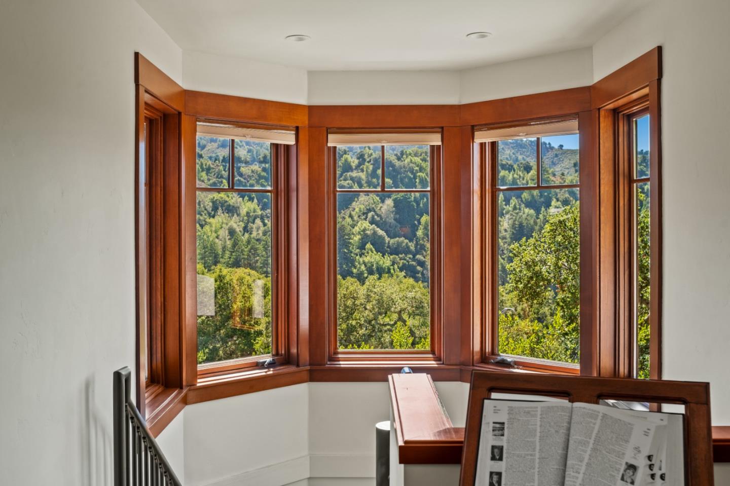 Room with curved wood-trimmed windows overlooking wooded hills.