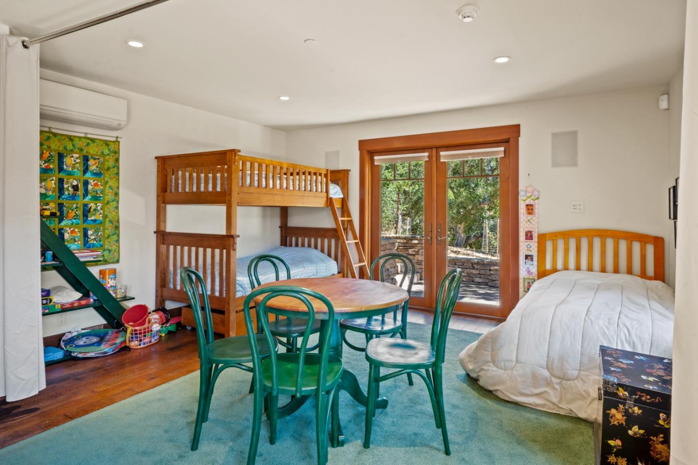 Bedroom with wooden bunk beds, a separate bed, and glass doors opening to a garden patio.