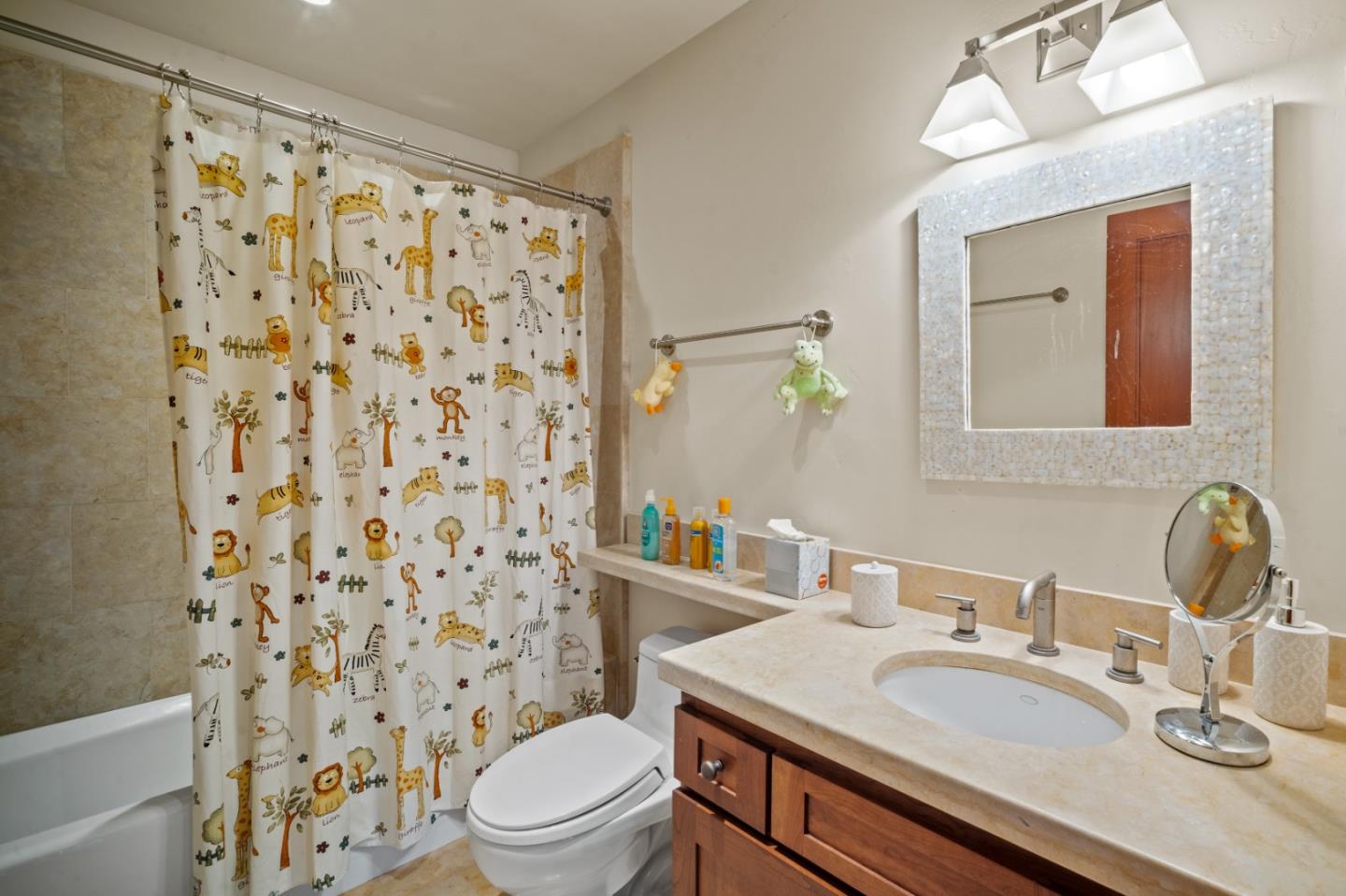 Bathroom with animal-print shower curtain, bathtub, and beige stone vanity.