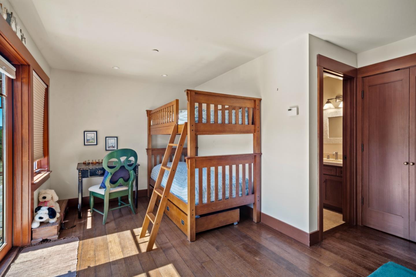 Bedroom with wooden bunk beds, dark hardwood floors, and an adjoining bathroom doorway.