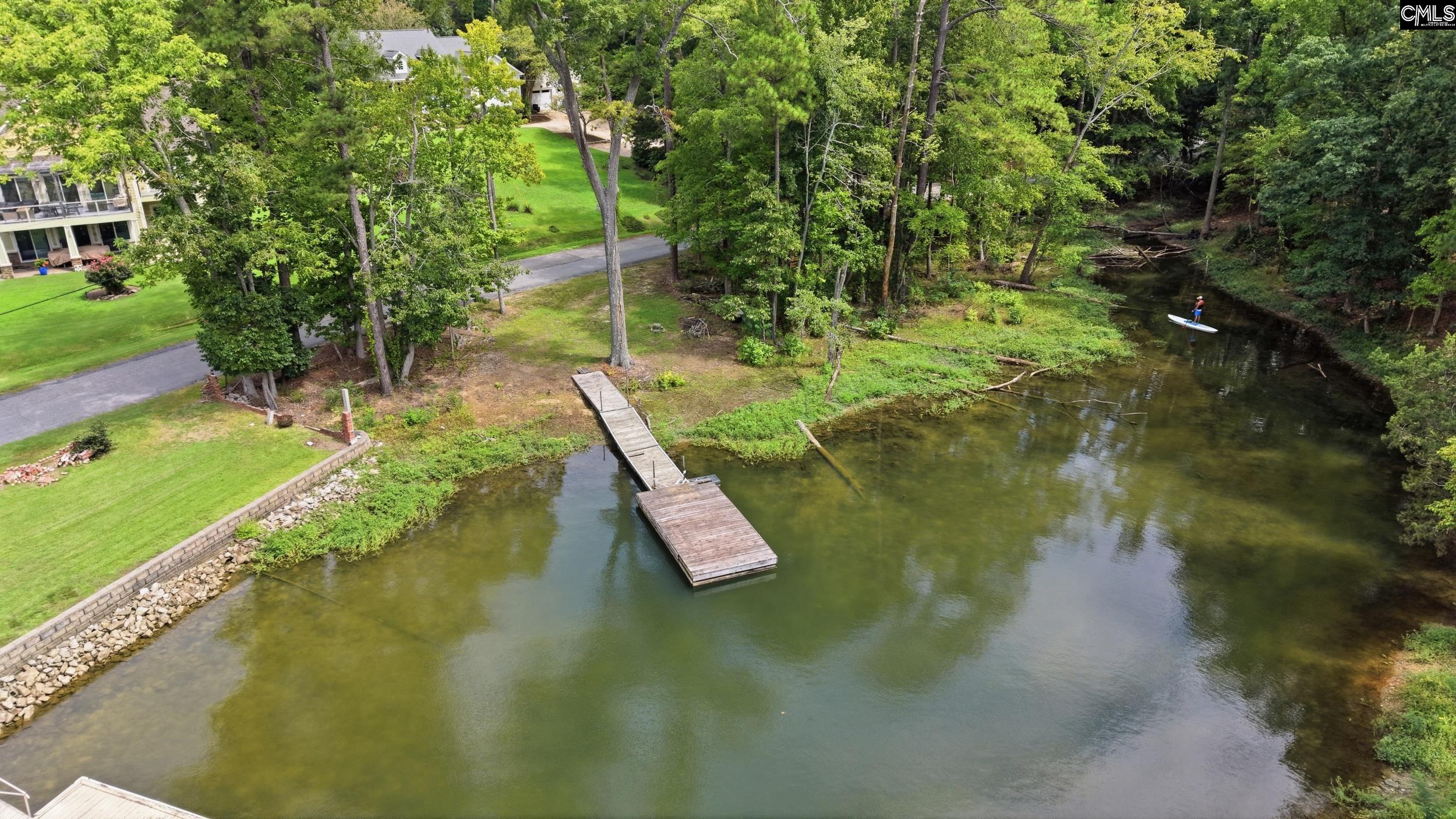 Wooded waterfront with a long dock extending into calm water.