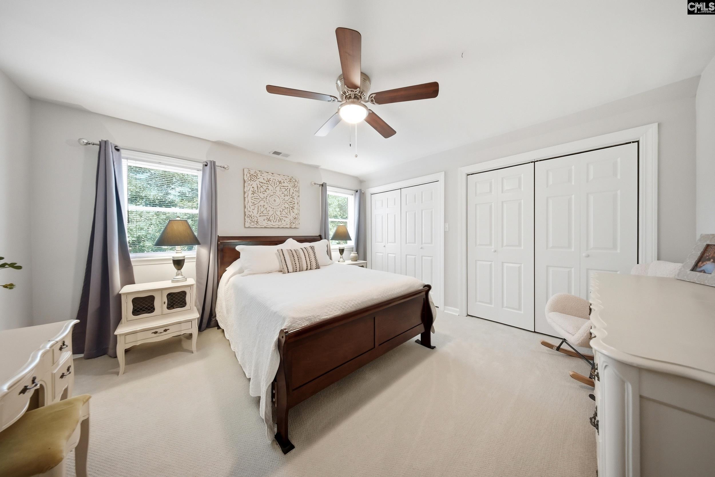 Bedroom with a dark wood bed, white bedding, gray curtains, and large closets.