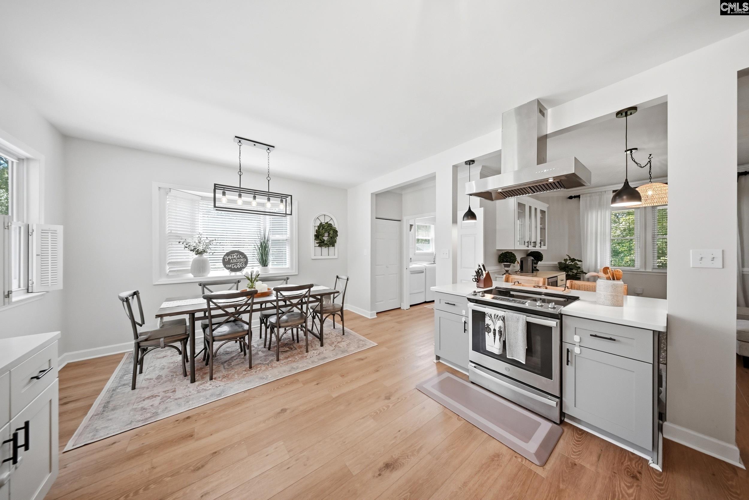 Open-plan kitchen and dining area with a stainless-steel range and a table by the window.