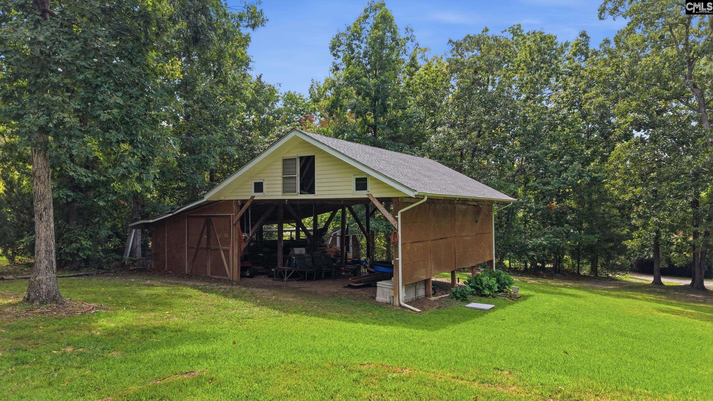 Raised covered structure with brown lattice sides on a lawn surrounded by trees.