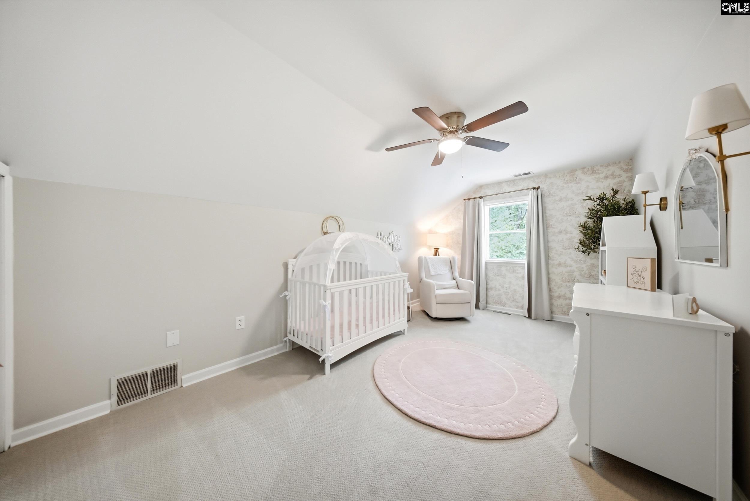 Nursery with a white crib, glider, changing table, and pale pink rug.