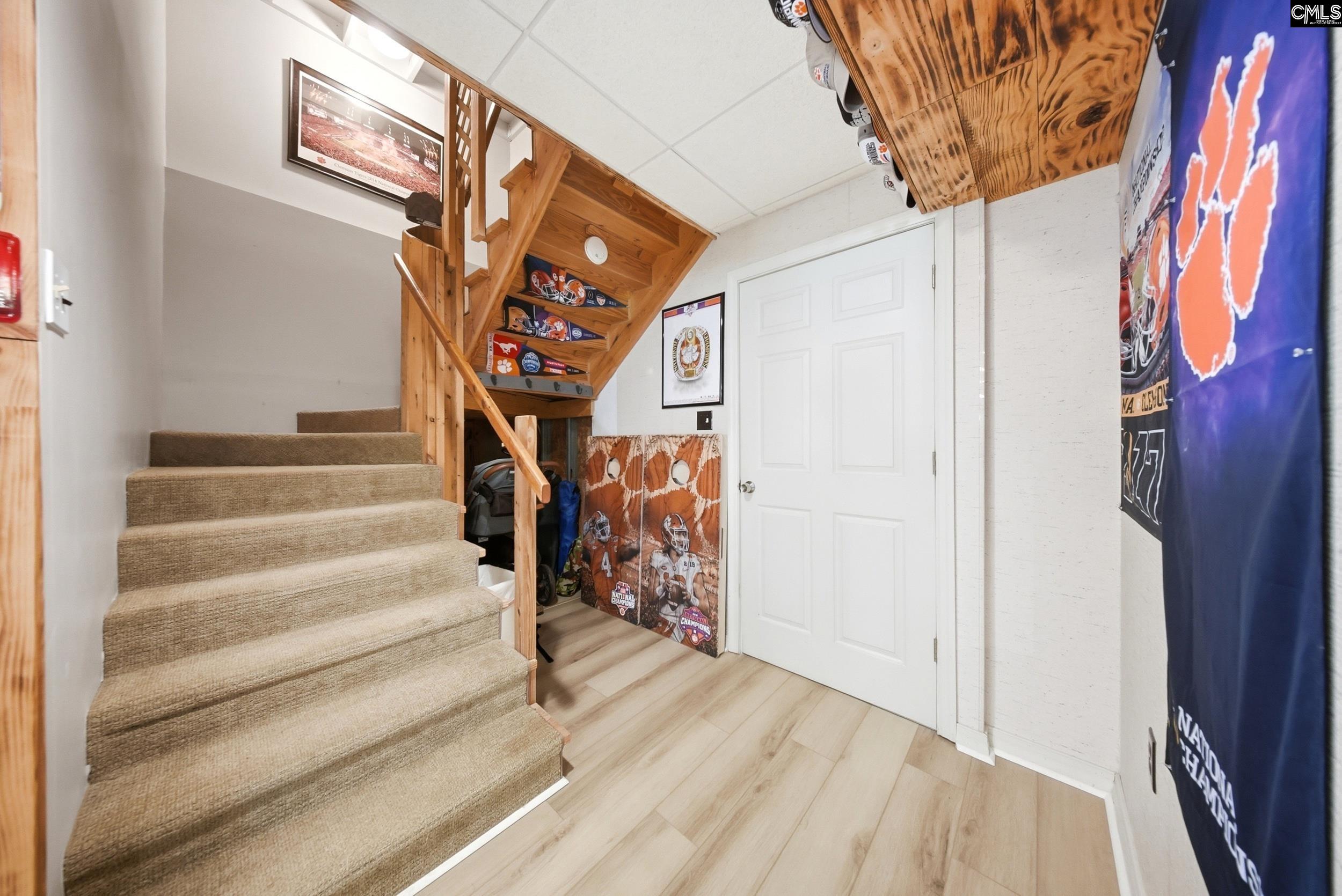Carpeted staircase with wooden railing and sports memorabilia displayed beneath and beside the stairs.