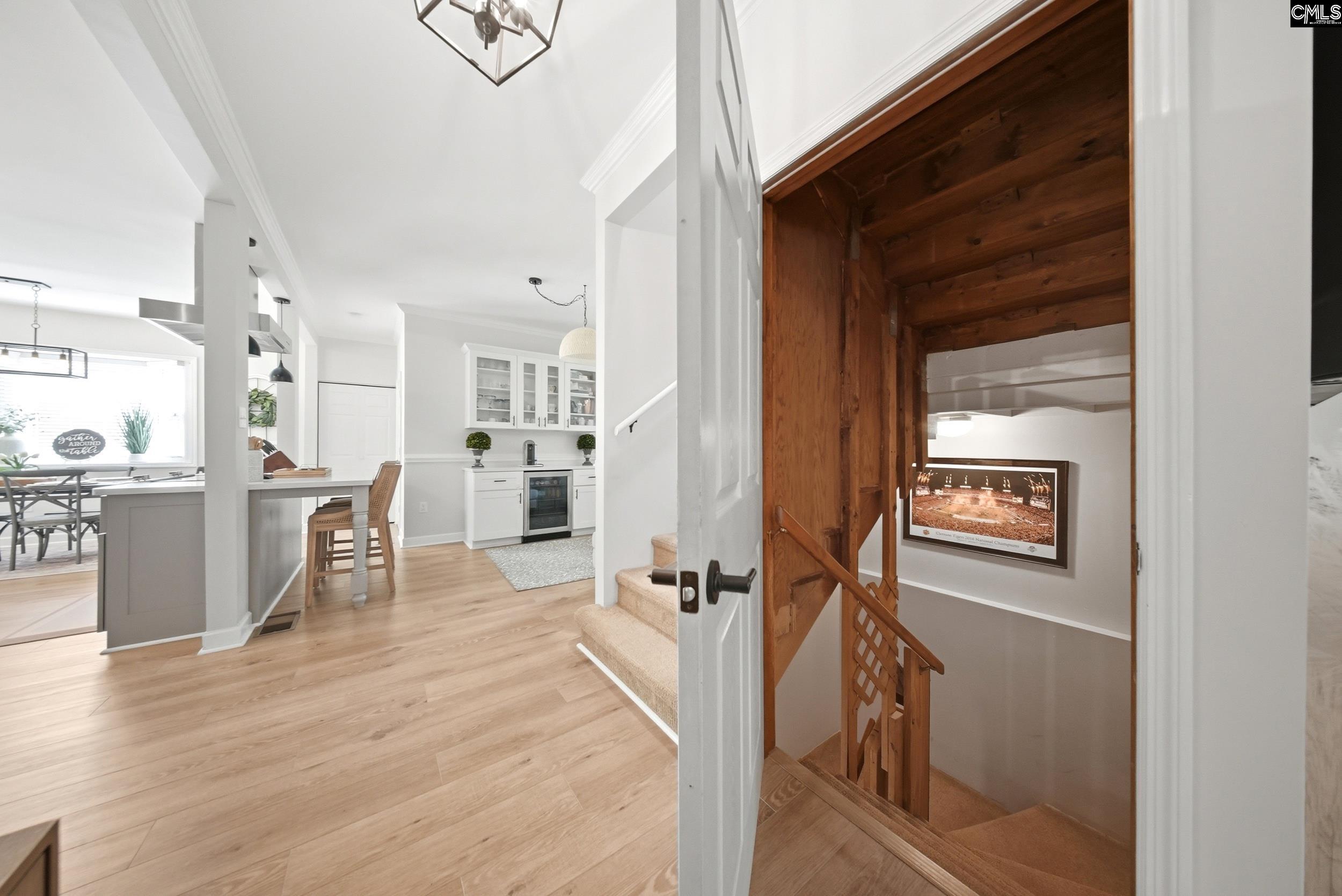 Open kitchen and dining area beside a wood-lined staircase with a framed poster.