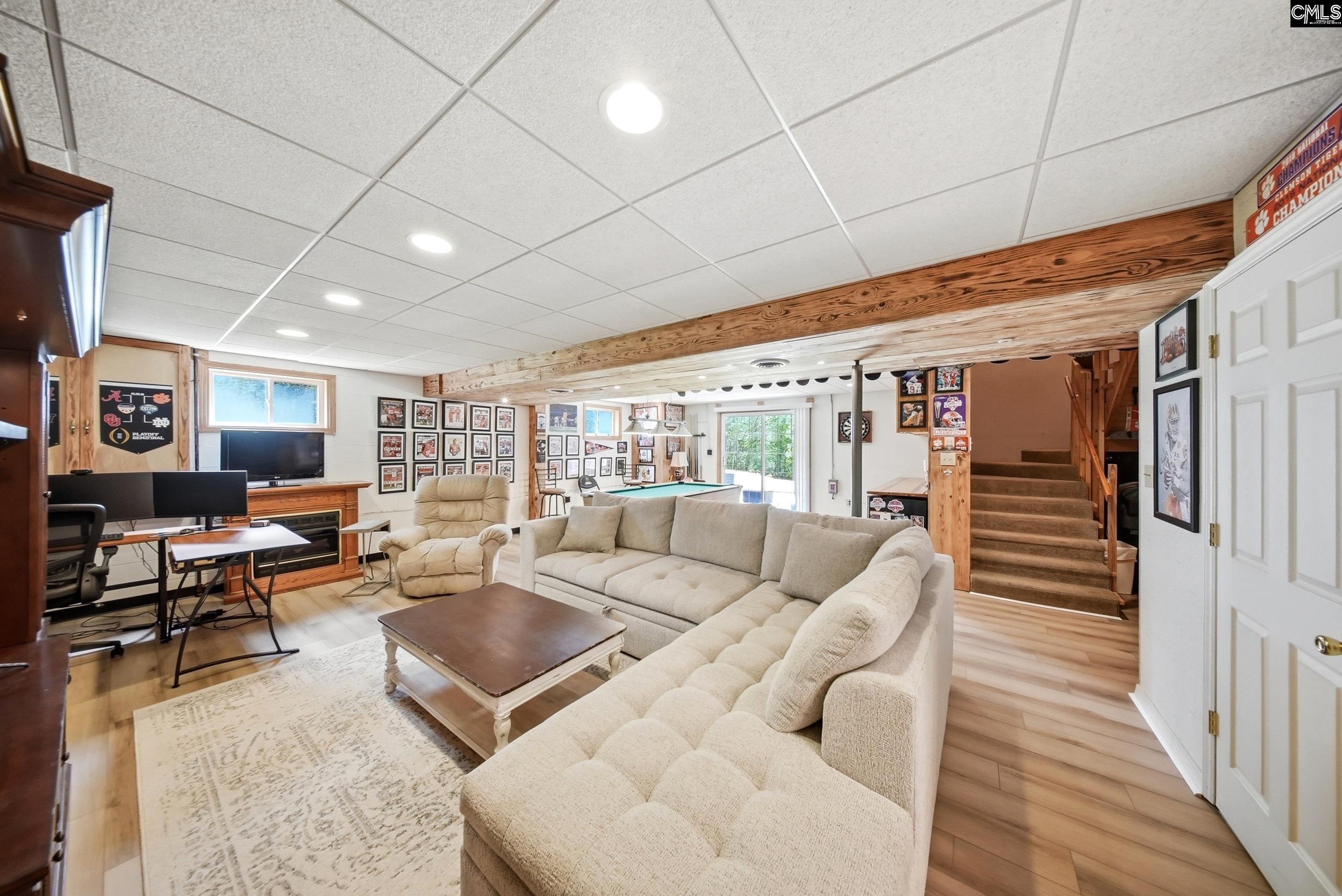 Furnished family room with a large sectional, pool table, sports memorabilia, and staircase.